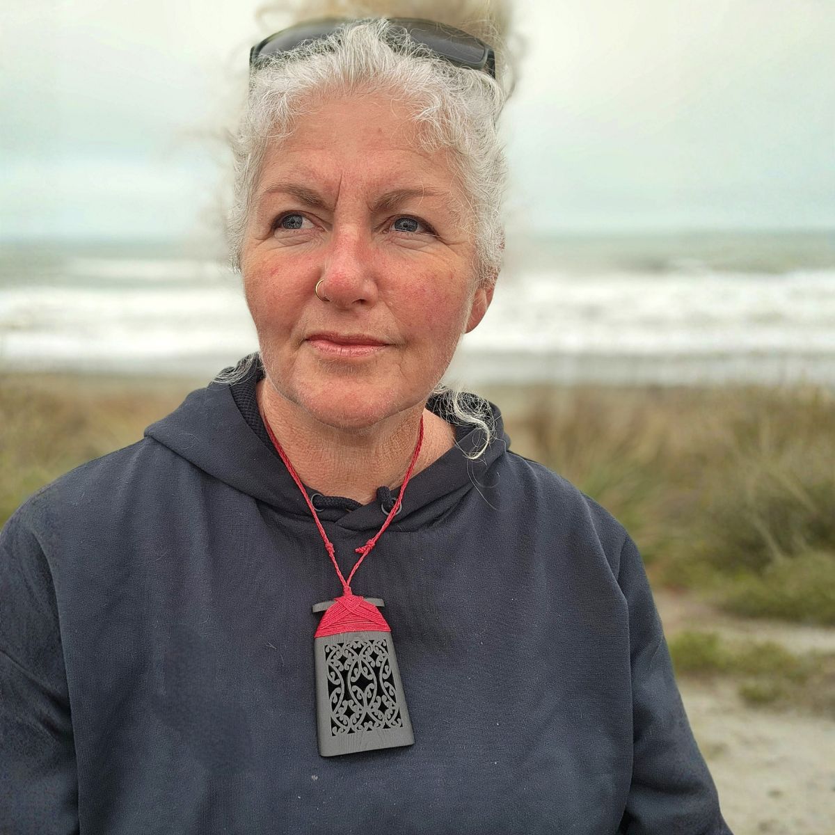 model at the beach wearing ebony wood toki pendant with red binding