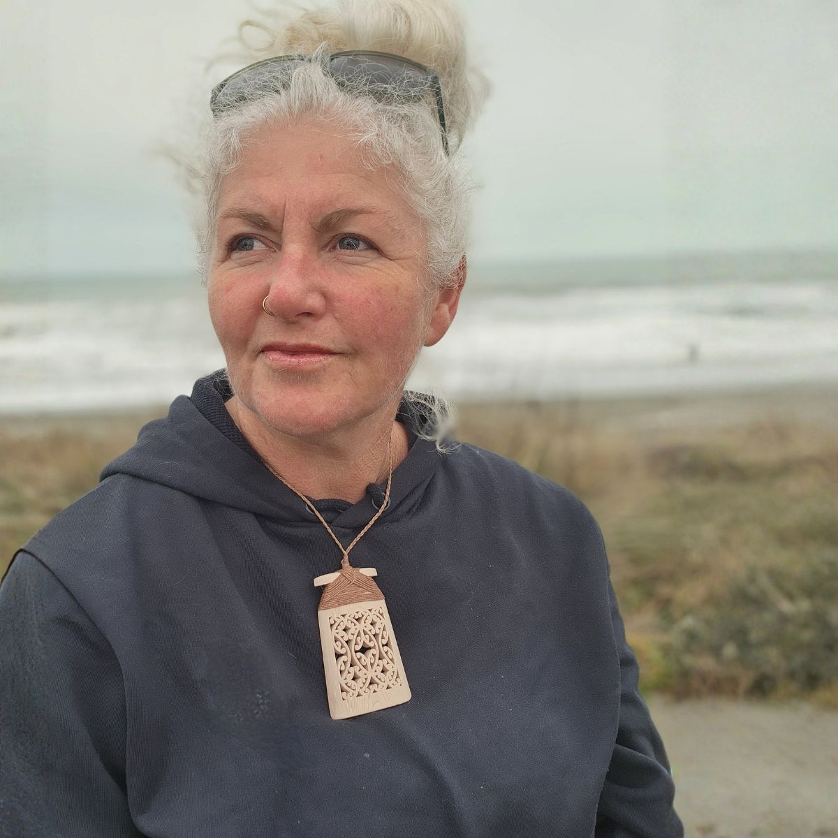 model at the beach wearing bone coloured 3d printed toki necklace with brown binding and cord