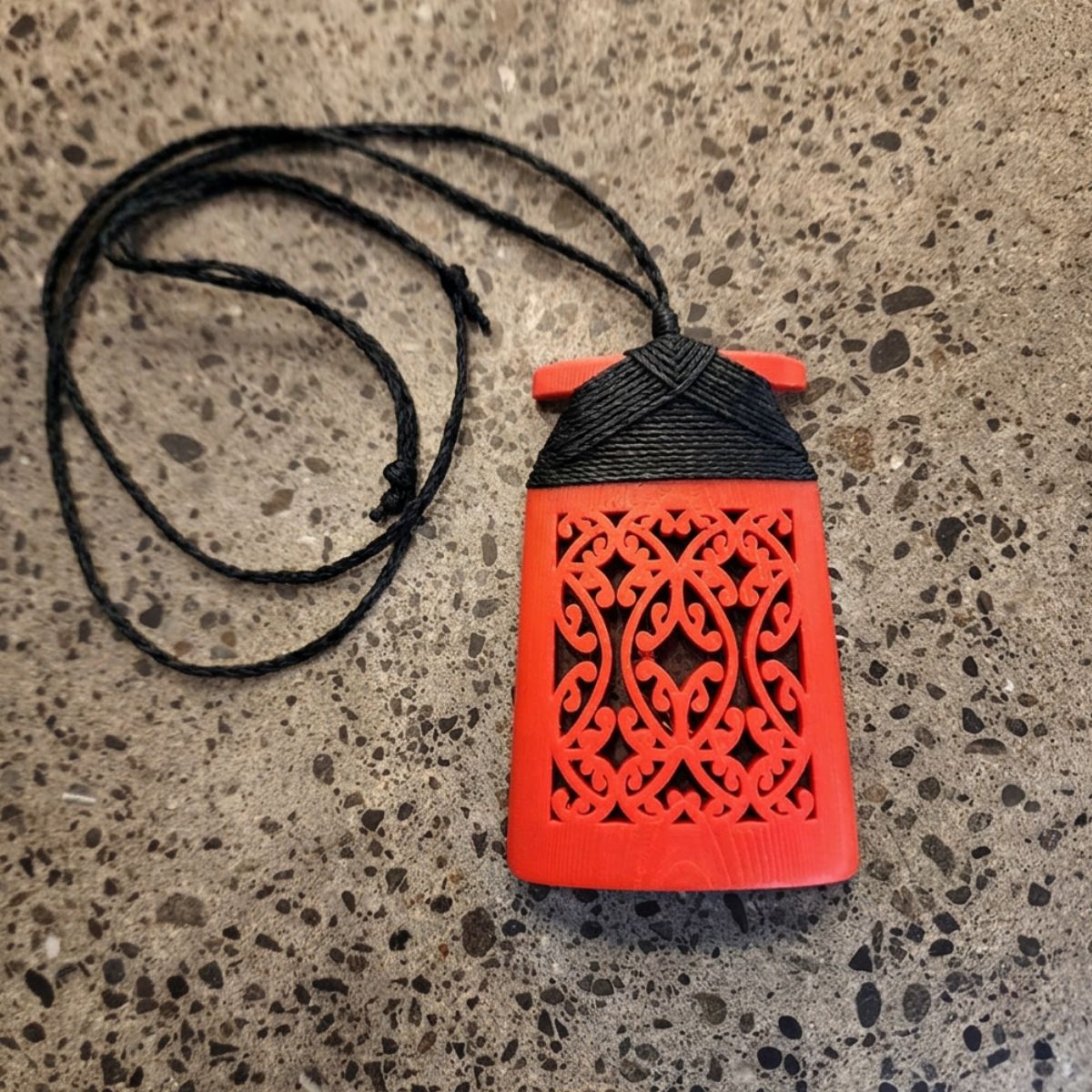 red coloured toki necklace with black binding and cord