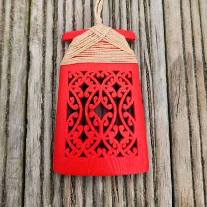 red coloured 3d printed toki necklace with natural coloured binding and cord, on a wooden surface, front view