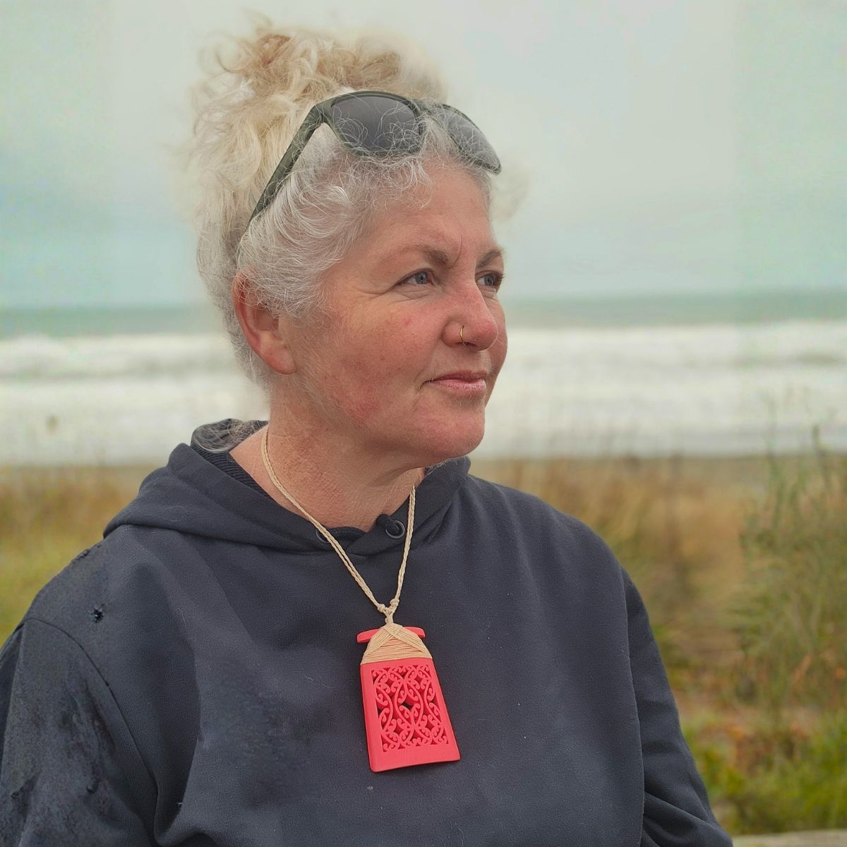 model at the beach wearing red coloured 3d printed toki necklace with natural binding