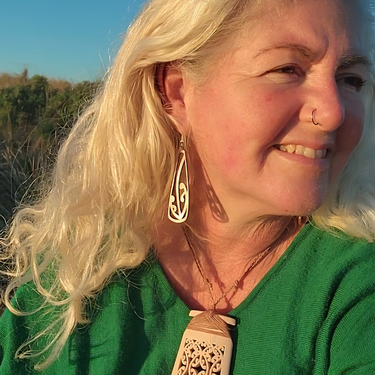 model wearing copper mangōpare earrings at the beach in the dawn sunlight