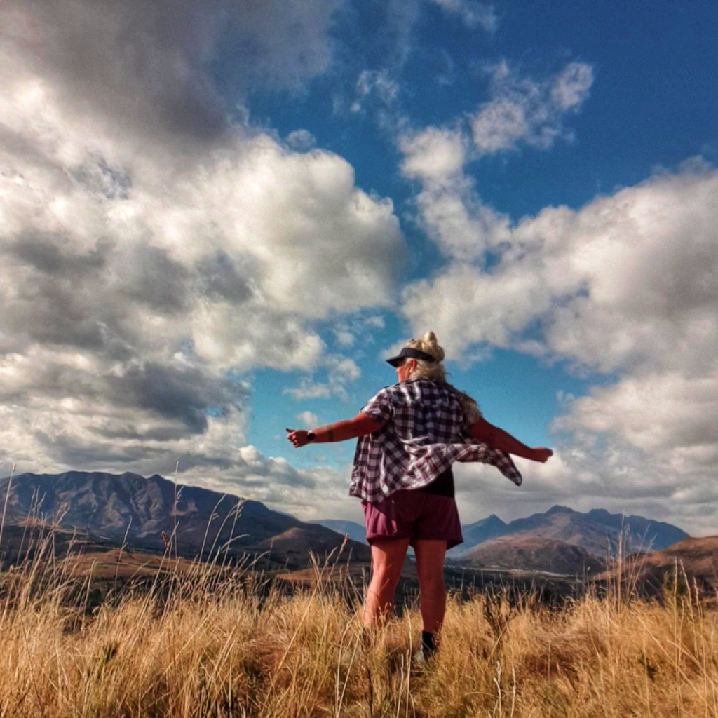 woman standing at the top of a mountain in the sun