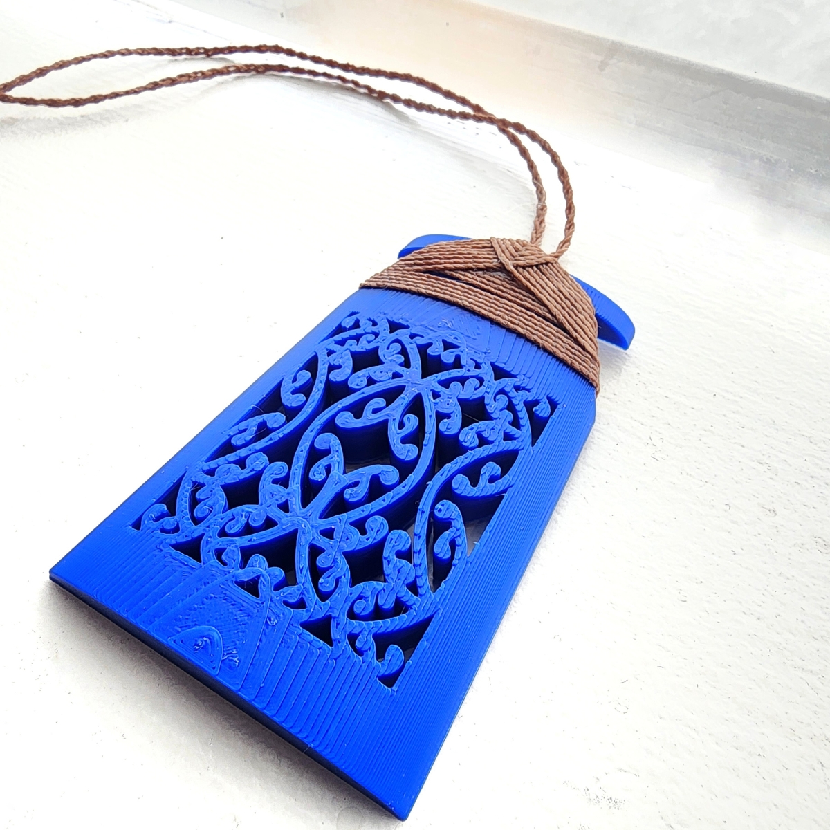 blue toki necklace on a white background with brown binding
