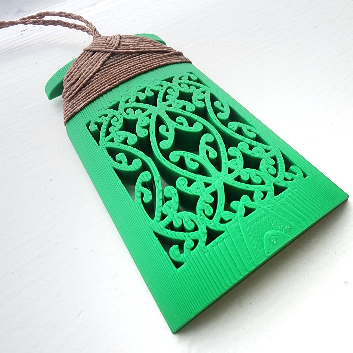 Green toki necklace with brown binding closeup of mangopare design on white background