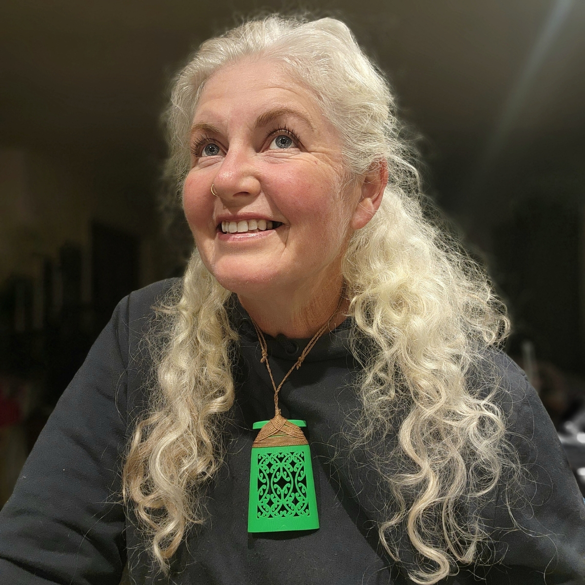 Green toki necklace on smiling woman with white hair