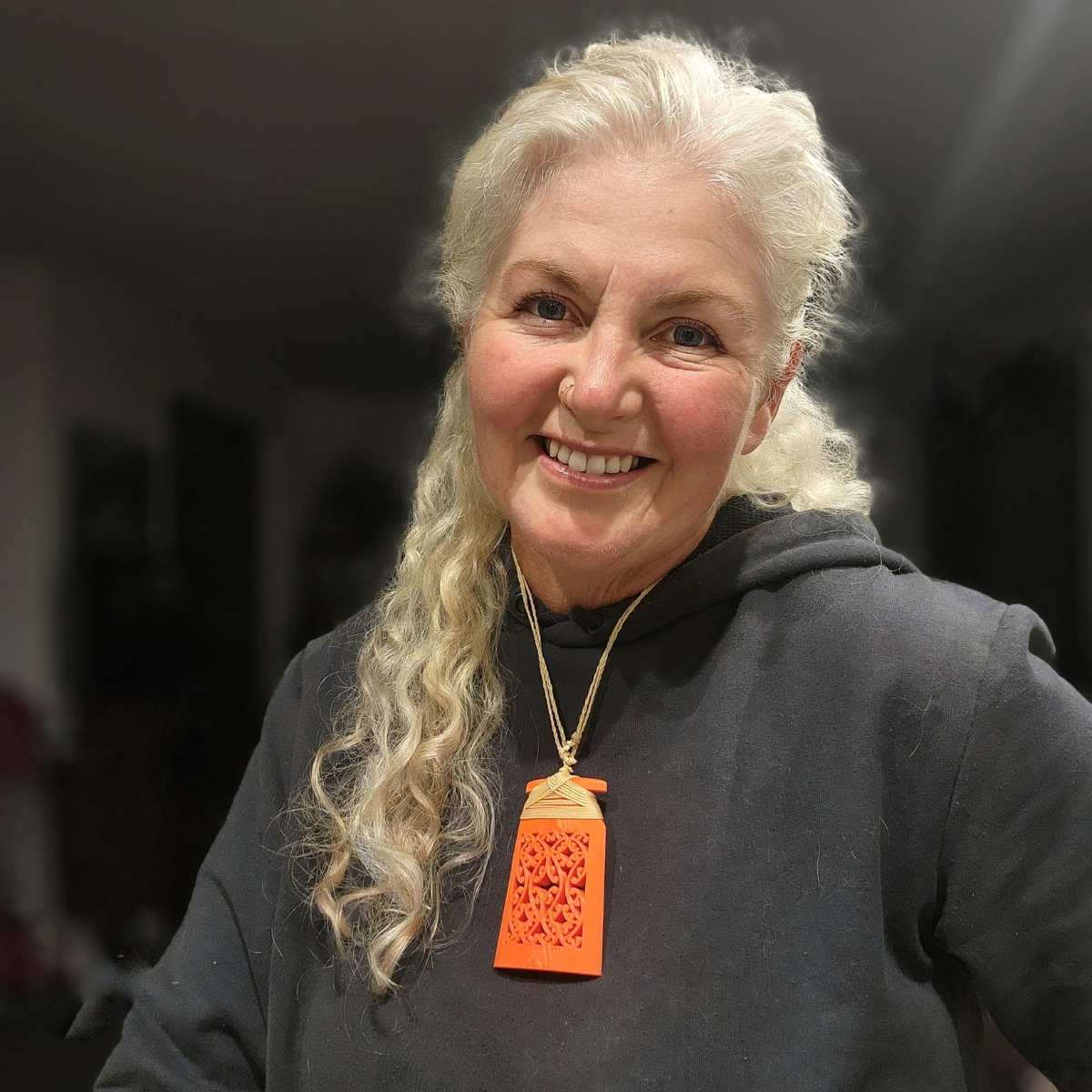 smiling woman with long white hair wearing orange toki necklace
